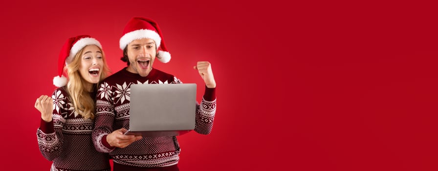 Special offer for Xmas. Excited man and his girlfriend with laptop computer gesturing YES over red background photo