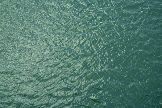 Top view of calm water surface texture with soft natural ripples. Background for eco-friendly design, peaceful concepts, and water sustainability. Blue green lake surface water background. photo