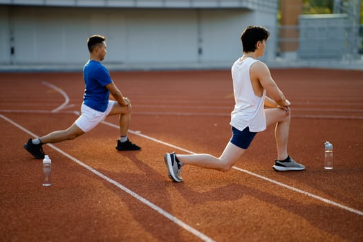 Two asian athlete men are stretching their legs muscles together on the racetrack in sports stadium. photo