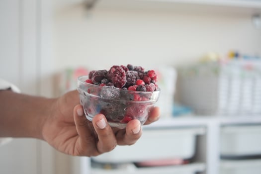 Holding a bowl of mixed frozen berries in a kitchen photo