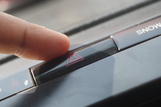 Finger pressing hazard light button inside vehicle photo