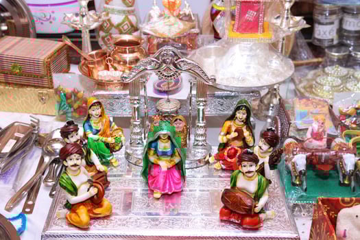 A rich display of traditional Indian clay dolls and metallic puja items.The scene is full of cultural vibrance, symbolic figures, and festive gifting items popular during Diwali or weddings. photo