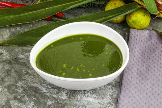 A bowl of green soup next to a plate of vegetables photo