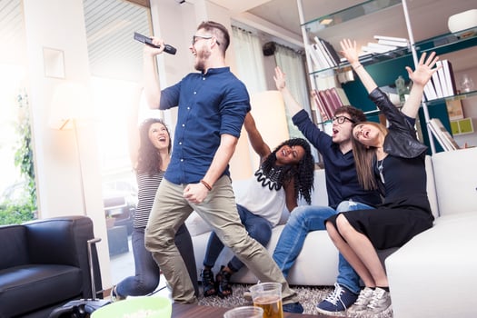 multi-ethnic group of enthusiastic friends having fun doing karaoke sitting on the sofa in a modern apartment photo