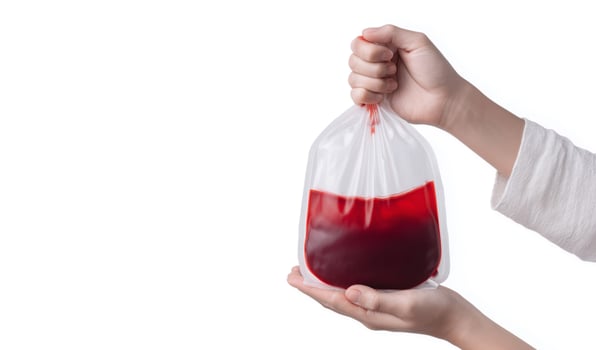 A hand holds a transparent bag filled with red liquid, symbolizing blood. photo