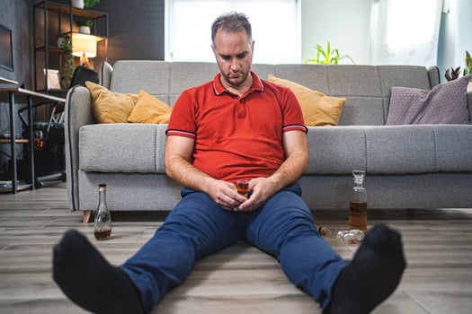 Drunk man sitting on the floor while drinking alcohol photo