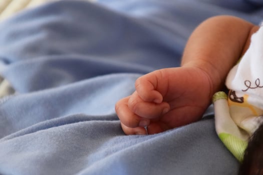 Close up of Indonesian baby hands on bed photo