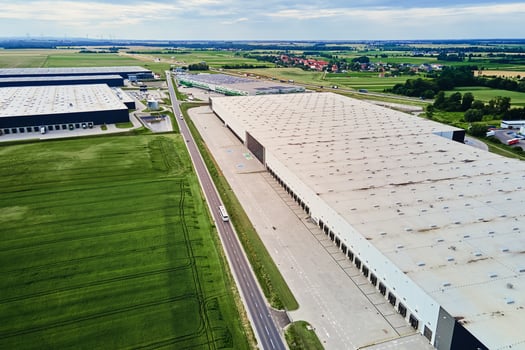 Large warehouse building with loading docks in green rural landscape photo