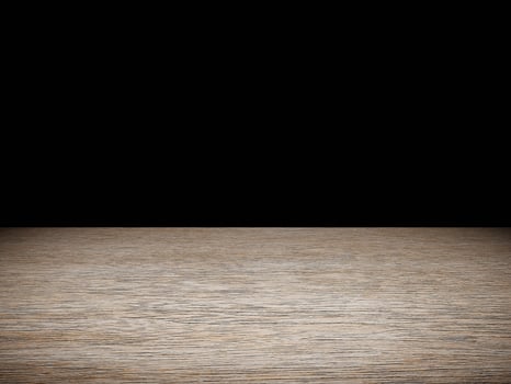 Softly illuminated wood table showcasing its texture, contrasted by a deep black background. photo