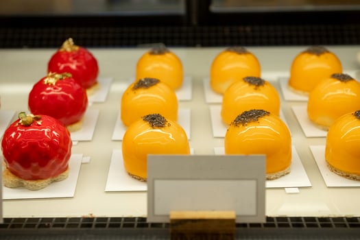 Orange and red dome-shaped pastries with glossy glaze on display. photo