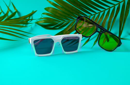 Trendy sunglasses on color wall with palm leaves. photo