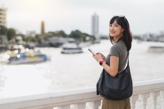 Young southeast asian woman teenager blogger world travel explorer searching smartphone map guide for local cultural experience. Asia tourism concept in Bangkok Thailand by Chao Phraya river photo