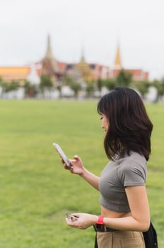 Solo Southeast Asian woman teenager blogger on world travel enjoys local cultural experience in Bangkok Thailand. explorer uses smartphone map guide to explore Asia, popular tourism concept photo
