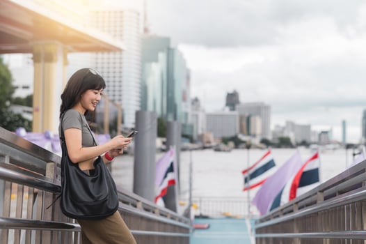 Happy young southeast asian woman and blogger searching map on smartphone. travel explorer on local cultural tourism experience in Bangkok Thailand near Chao Phraya river in Asia photo