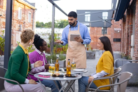 A waiter takes an order on a tablet from customers at an outdoor restaurant. photo