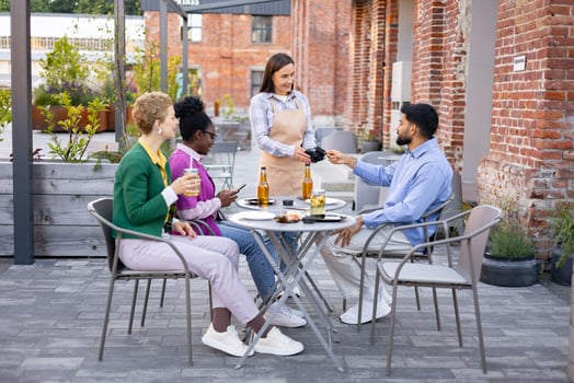 A female waiter at an outdoor cafe uses a portable terminal to process a customer's payment. photo