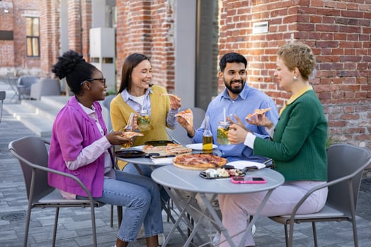 Group of diverse friends enjoying pizza and drinks at an outdoor restaurant, sharing smiles and laughter. photo