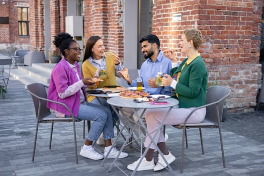 A diverse group of friends enjoys pizza and drinks together at an outdoor cafe. photo