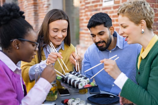 Diverse group of friends enjoys sushi and drinks together at an outdoor restaurant. photo