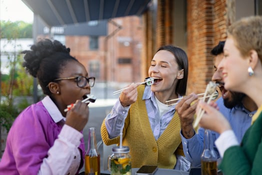 Diverse group of friends enjoying sushi outdoors, laughing and having a good time during a casual lunch. photo