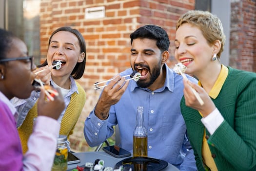 A diverse group of friends enjoys a sushi meal together, savoring the flavors and company outdoors. photo