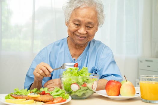Asian elderly woman patient eating salmon steak photo