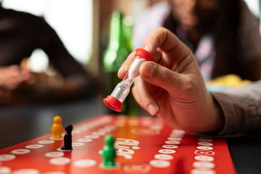 Selective focus on male individual setting hourglass timer for board game. Closeup shot capturing playful nature of game and adds sense of time management to friendly competition. photo