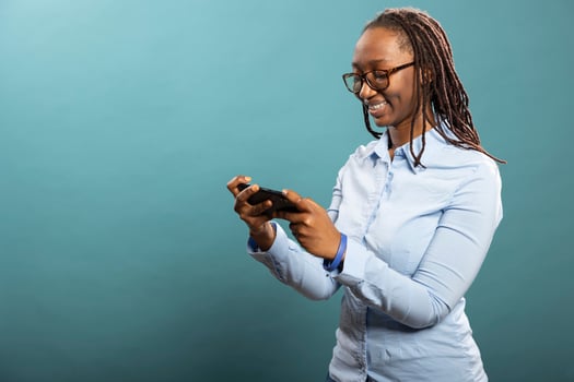 Portrait of african american woman playing games on her mobile phone, engaged in interactive entertainment. Cheerful black female model standing and looking at her cellphone. photo