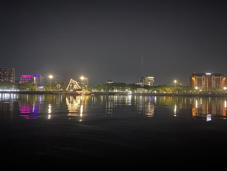City lights shimmer and reflect on the tranquil water at night creating a peaceful scene. photo
