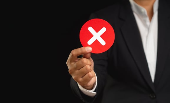 Businessman in a suit holding a cross symbol while standing on a black backgroun photo