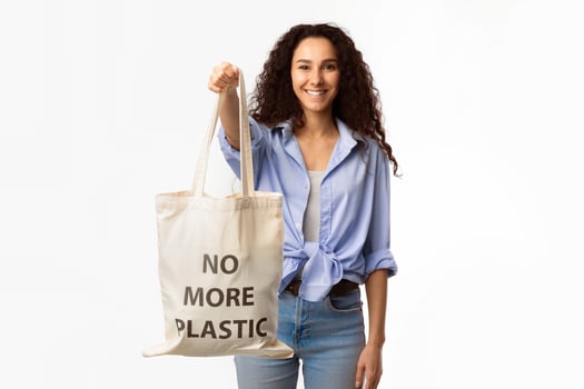 No More Plastic. Smiling Lady Showing Eco Shopper Bag With Inscription Standing On White Background In Studio. Conscious Consumption And Ecology Protection Concept photo