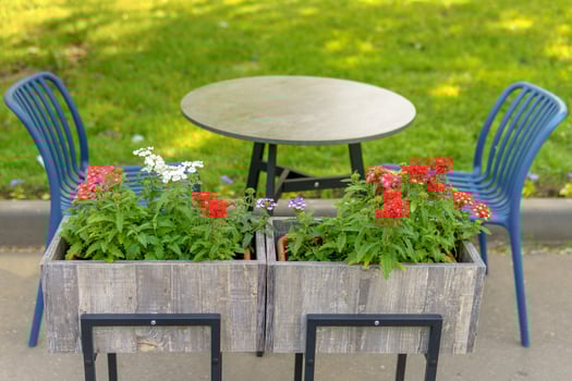 Table and chairs in a street cafe. A flower box is in the foreground. photo