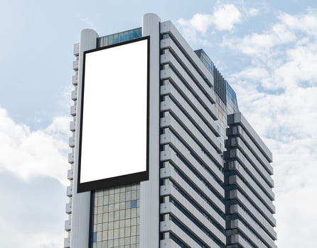 Mock up white vertical large LED display billboard on tower building with blue sky background . Clipping path for mockup photo