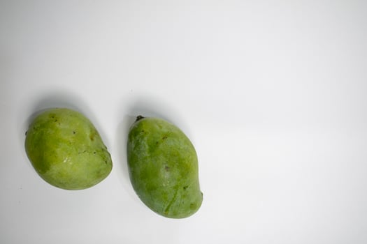 Two green mangoes placed on a clean white background, creating a minimal and fresh look. photo