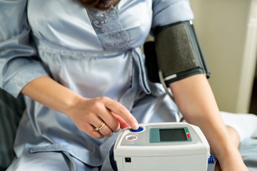A woman in a blue dress is using an electronic blood pressure monitor photo
