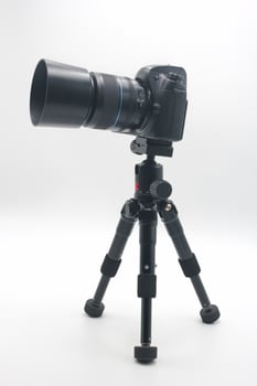 Perfectly positioned camera set up on a sturdy tripod against a clean white background for photography projects or studio work photo