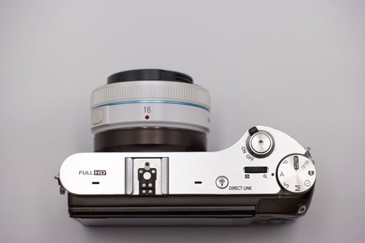 Camera with modern design showcasing control settings and lens details on a neutral background photo