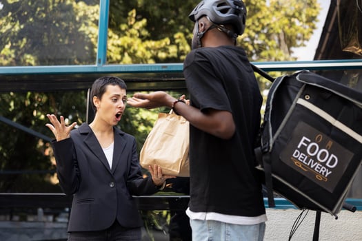 African american delivery man handing over wrong food package, dealing with the mad and dissatisfied customer. Woman refuses the takeaway order, clearly frustrated by poor delivery. photo