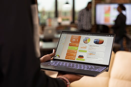 Closeup of african american professional analyzing performance metrics on laptop with selective focus on financial charts. Device screen showing business analytics as black individual reviews KPI data photo