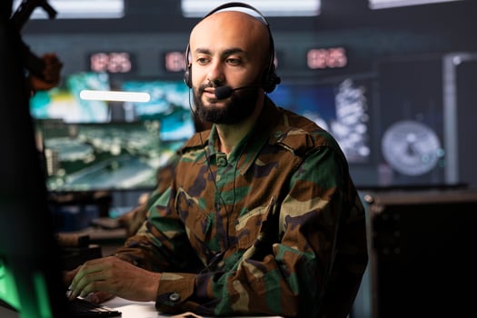 Agent in command room uses military tech to identify threats from enemies. Army operator in base of operations uses headset mic to communicate information to generals on war front line photo