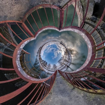 A circular view of the sky and clouds from inside a spiral staircase photo