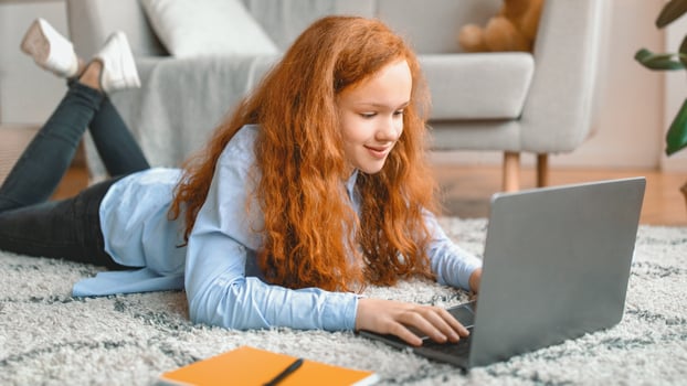 Girl using laptop while lying on rug photo