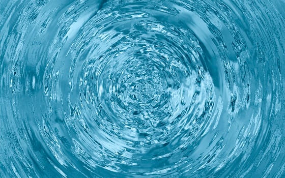 Vortex of swirling clear water with reflections and turbulence captured in a top-down motion blur spiral pattern photo