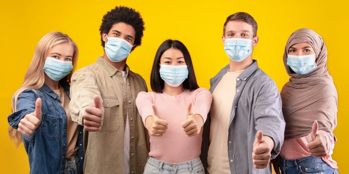 Group of friends giving thumbs up with masks photo