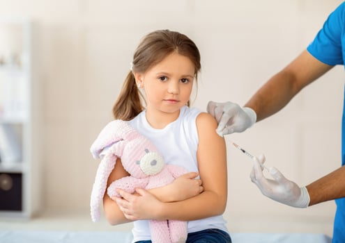 Lovely little girl with toy rabbit receiving covid-19 vaccine injection at clinic. Cute kid getting coronavirus immunization at hospital. Protection against global virus concept photo