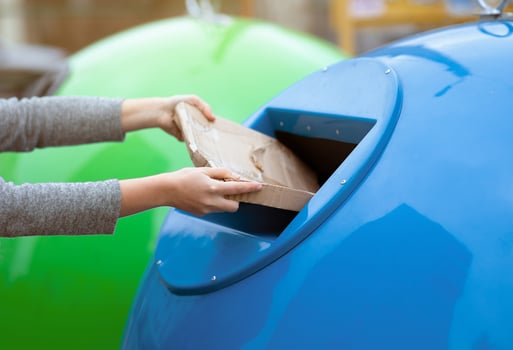 Paperwaste Sorting. Unrecognizable woman throwing carton package into blue garbage recycle bin outdoors, eco-friendly lady caring about environment, cropped image with selective focus photo
