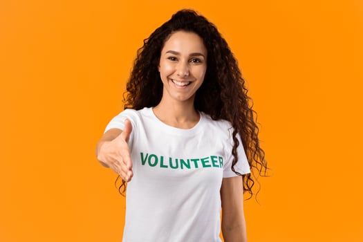 Cheerful Volunteer Woman Offering Hand For Handshake Greeting To Camera Posing Standing Over Yellow Studio Background. Volunteering, Voluntary Work, Join Our Team Concept photo