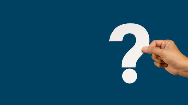 Hand holding a white question mark symbol against a blue background photo