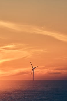 Wind turbine at sunset over ocean photo