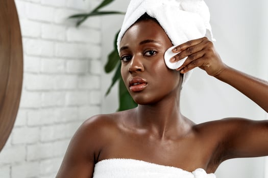 Woman caring for her skin while looking into a mirror in a bright bathroom photo